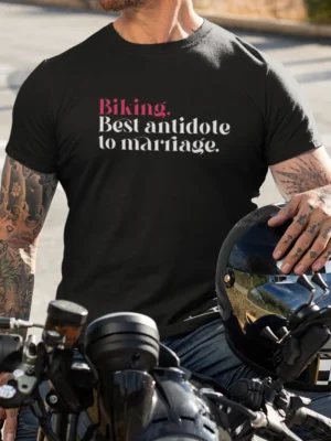 “Biking. Best antidote to marriage.” typography graphic printed in pink and white on a black t-shirt worn by a biker sitting on a motorcycle | Smolt