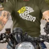 “Torque Sera Sera” playful motorcycle typography graphic printed in yellow and white on an olive green t-shirt | Smolt